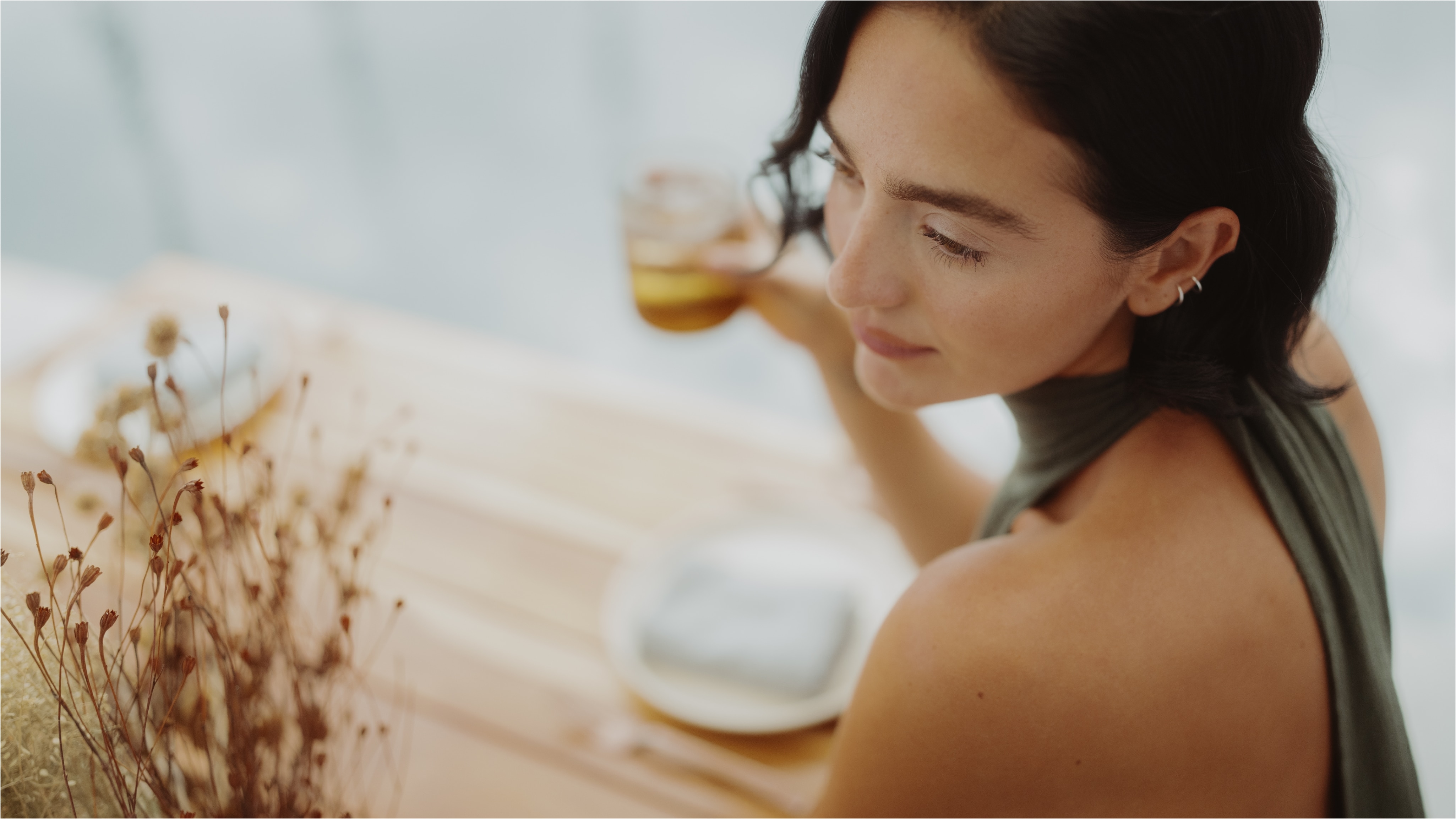 A woman in a sleeveless green top enjoying a drink at the Mandarin Oriental Residences and Resort in Kanai Riviera Maya.