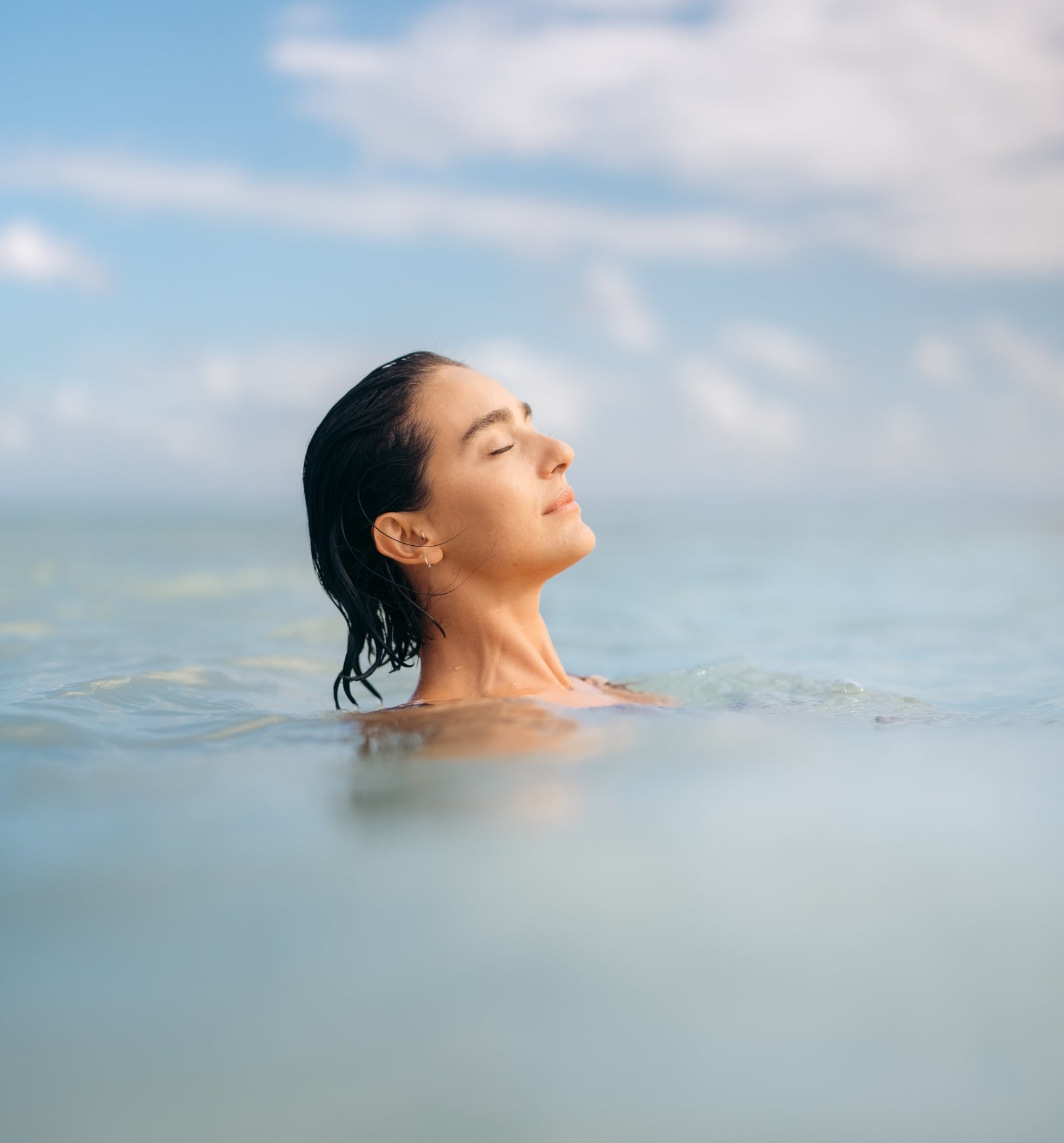 A woman enjoying a serene moment floating in calm water at Mandarin Oriental Residences in Kanai, Mexico.