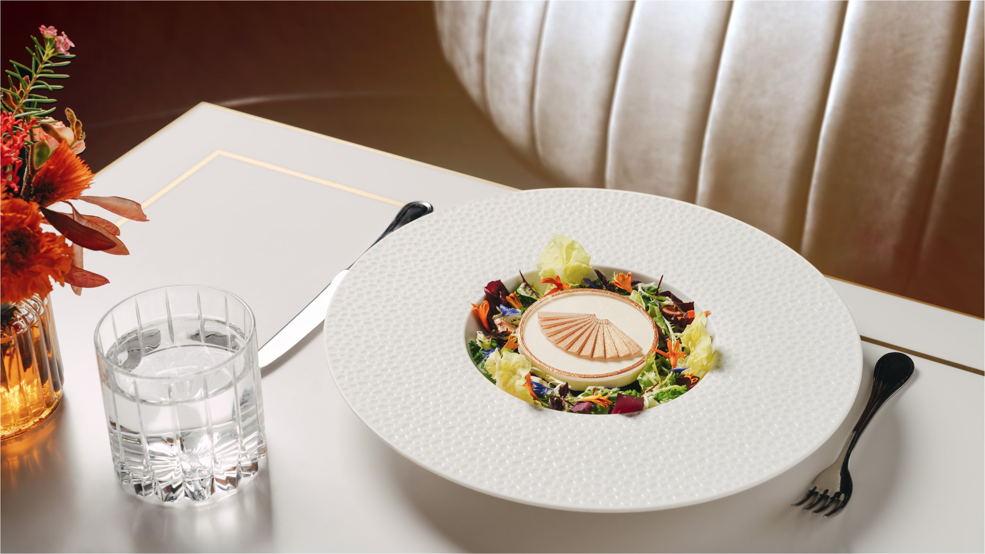 A fan-shaped crisp surrounded by a vibrant mixture of greens and edible flowers at the Mandarin Oriental Kanai restaurant.